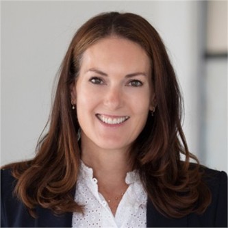 Naomi Grimwood in a black jacket and white blouse, in front of a pale background