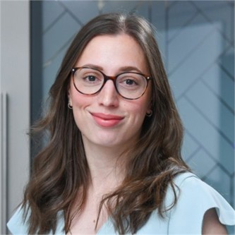 Hannah Reid in glasses and a pale blue top, in front of a geometric glass background