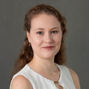 Lizzie Costello in a white sleeveless top, in front of a grey background