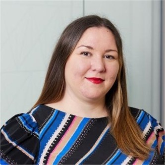 Ainslie Wilson-Shearer in a black and blue striped top, in front of a grey background
