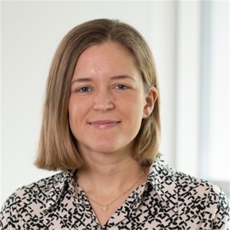 Lucy Brand in a cream and black geometric patterned blouse, in front of a pale background