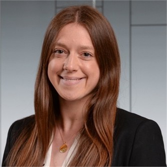 Natasha Hall in a black jacket, in front of a geometric glass background