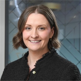 Poppy Wilkinson in a black jumper, in front of a geometric glass background