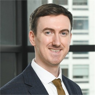 Fintan Corkerry in a navy suit and tie, in front of a window