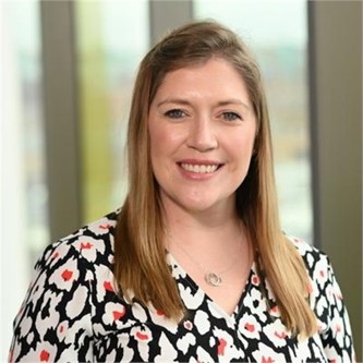 Kirsten Crawley in a black, white and red patterned top, in front of a window
