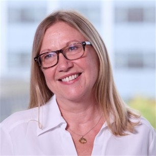 Clare Dodds in glasses and a white top, in front of a window