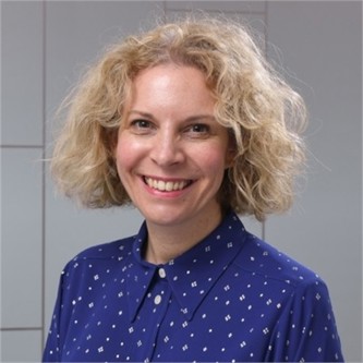 Laura Smith in a blue dotted shirt, in front of a geometric glass background