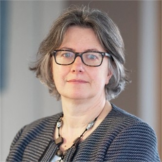 Deborah Clark in glasses and a dark top, in front of a grey background