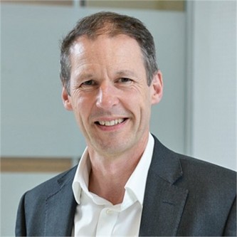 Kevin Lowe in a grey suit and white shirt, in front of a pale background