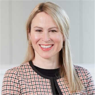 Carol Couse in a check jacket, in front of a pale background