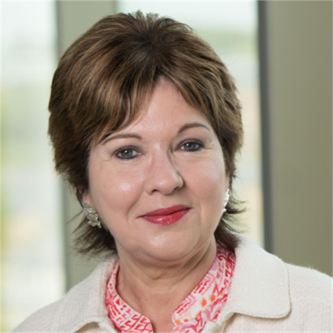 Laura Holdaway in a cream jacket and pink patterned shirt, in front of a window