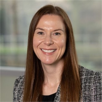 Carina Davis, in a black top, in front of a pale background
